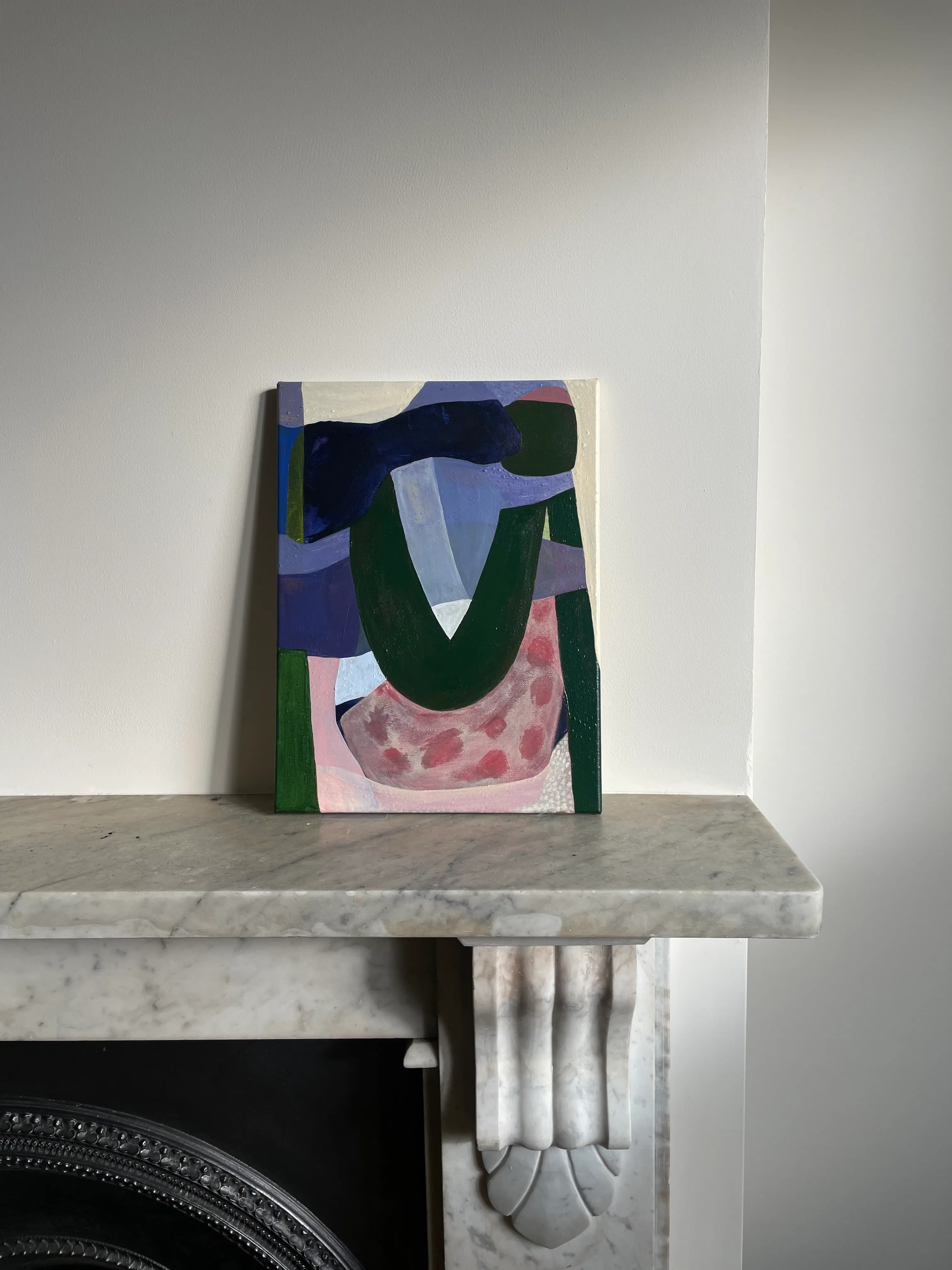 Abstract painting in navy, green and pink, resting on a marble mantelpiece