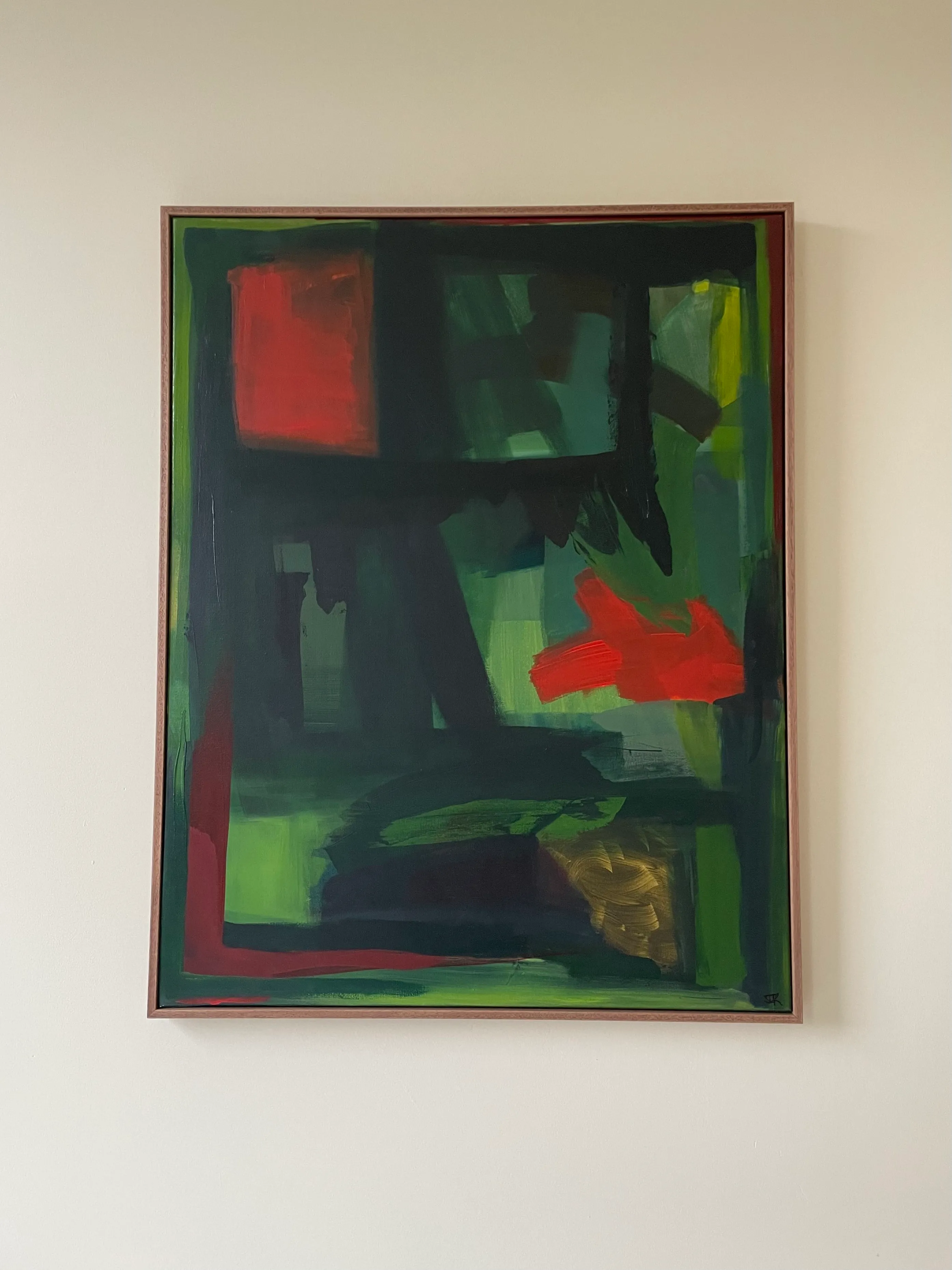 Framed abstract painting in dark greens with red accents